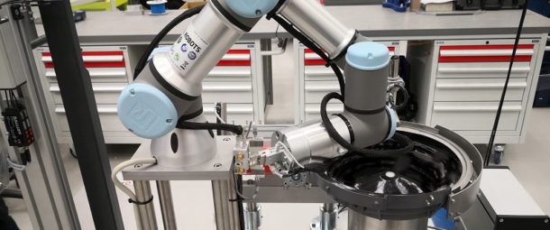 A UR3 collaborative robot is handling small terminal parts.