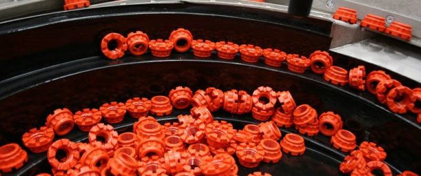 A vibratory bowl feeding and handling system is feeding and orientating red plastic nuts.