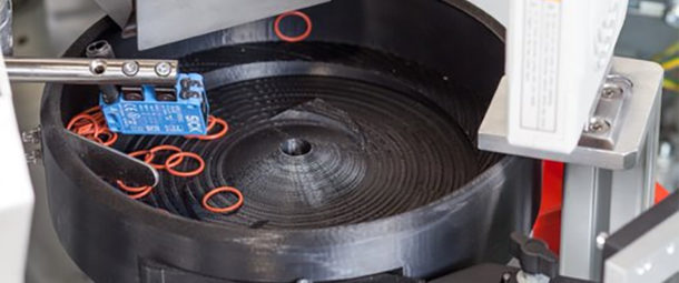 A 3D printed vibratory bowl feeder is handling red O-rings.